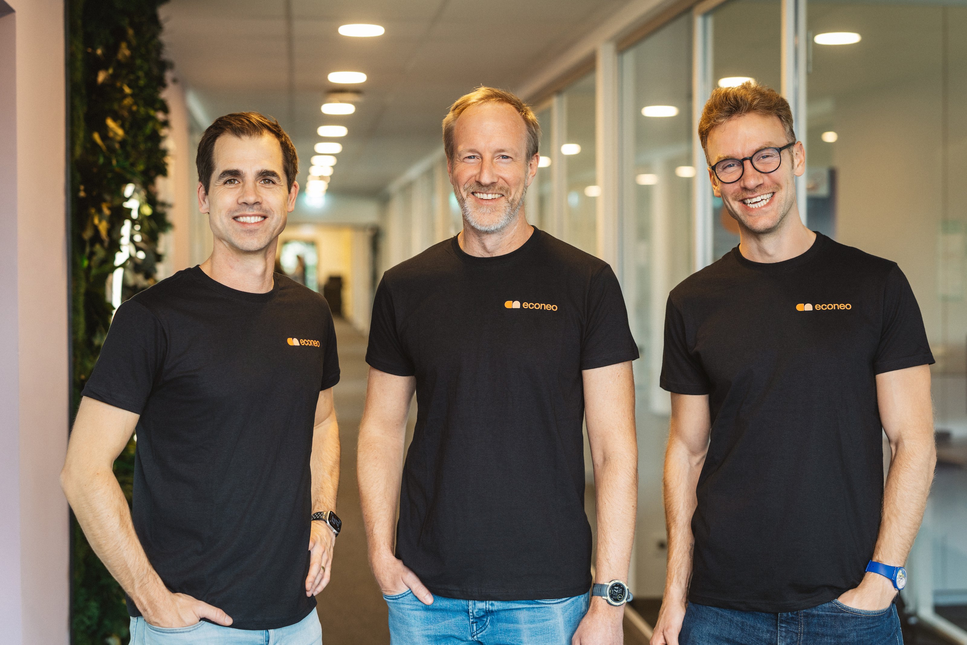 Patrick Mexner, Thomas Müller und Tilman Gartmeier, die drei Geschäftsführer von econeo energy, nebeneinander in einem Büroflur