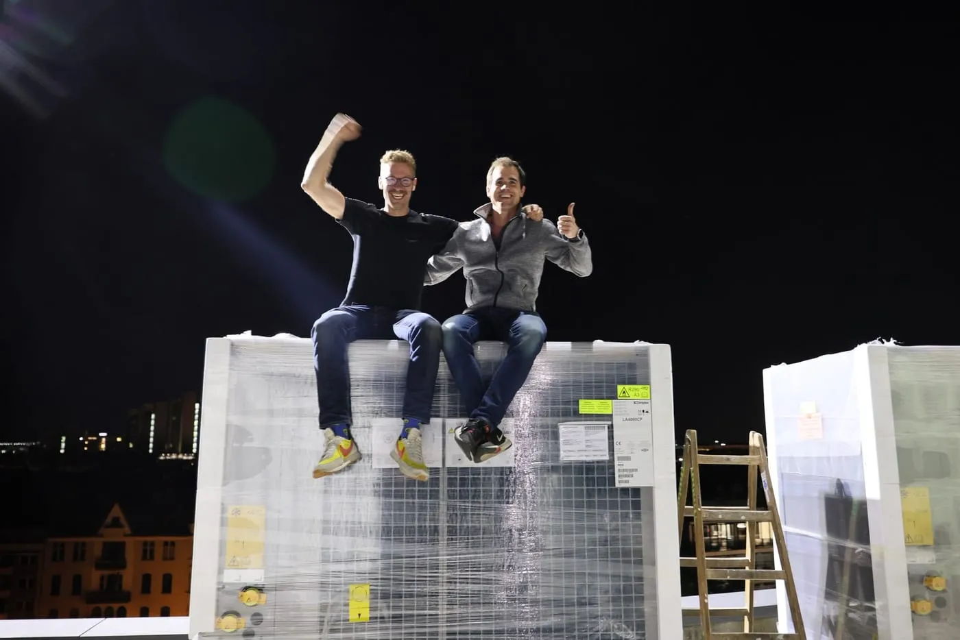 Das Montageteam auf den angelieferten Wärmepumpen vor der Kölner Skyline