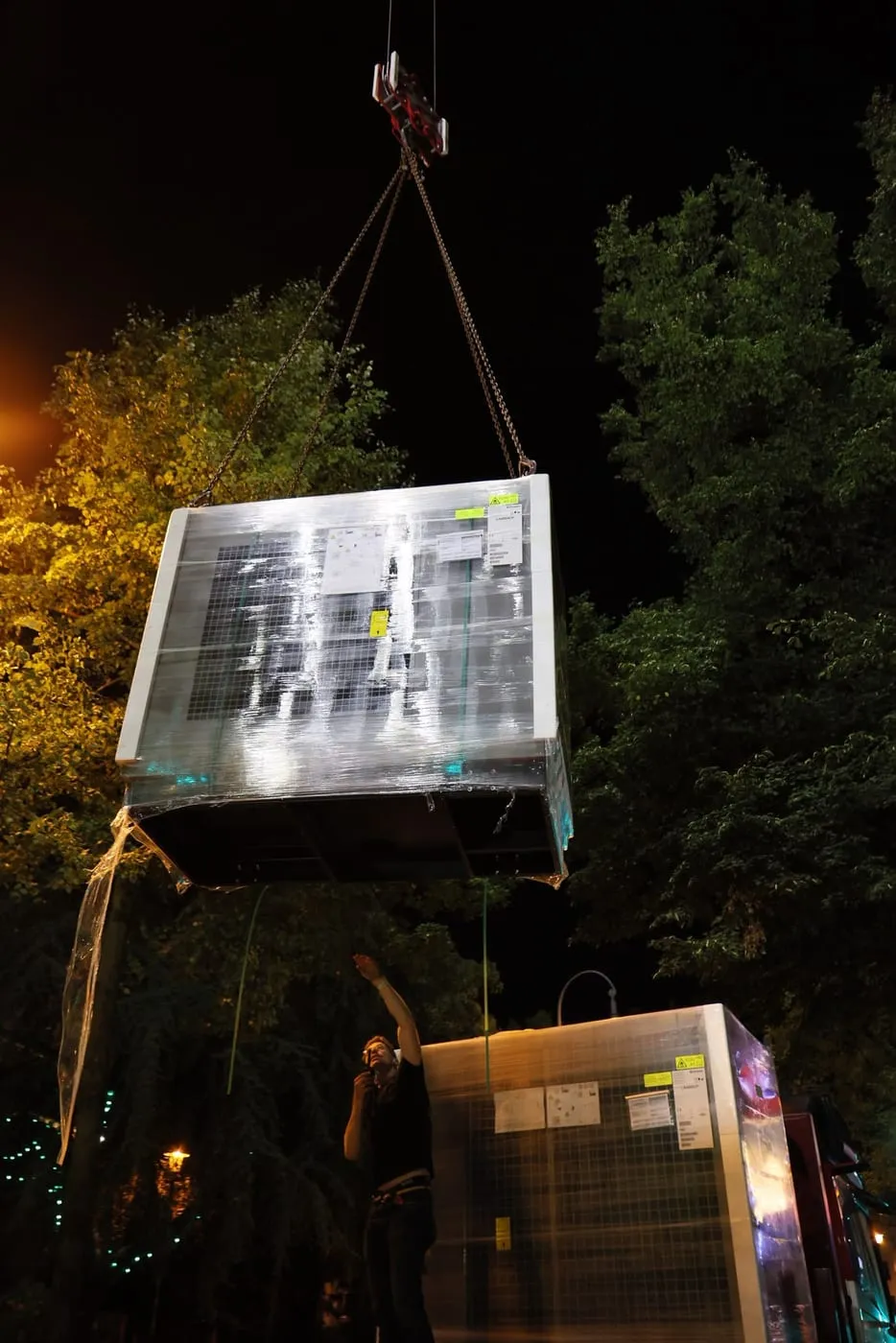 Verpackte Wärmepumpe schwebt zwischen Baumkronen zum Dach