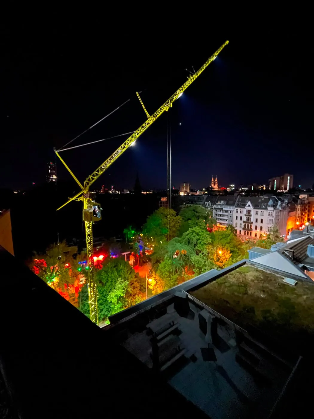 Blick von oben auf den beleuchteten Kran und die Baustelle bei Nacht