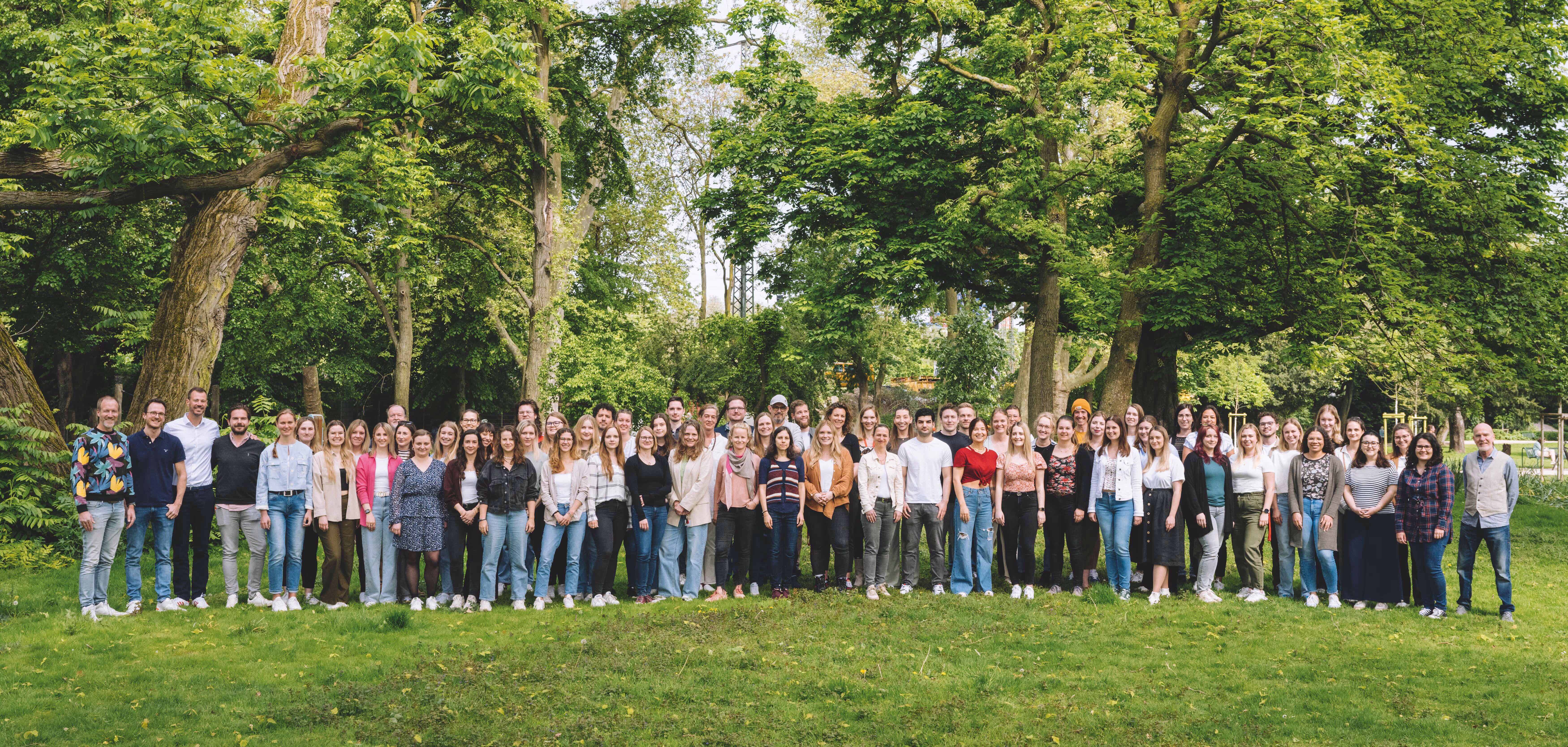 Gruppe von Menschen mit orangenen T-Shirts auf einer grünen Wiese 